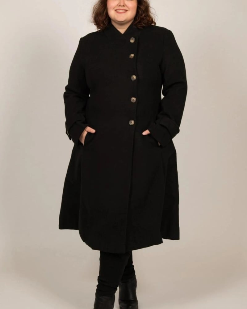 Front of a model wearing a size 2X Harper Retro Flared Coat Side Buttons in Black by ANNICK. | dia_product_style_image_id:309551